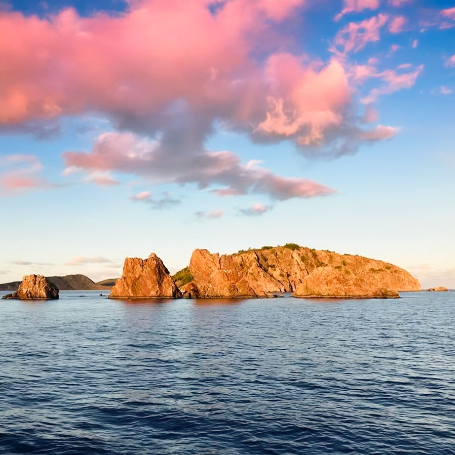 Beautiful dramatic Pink Clouds hover over the Indians, off Norman Island BVI during sunset during a sunset cruise with Celtic Powerboats.